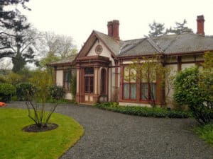 Front of Point Ellice House, a one storey heritage house with 2 chimneys, an assortment of early 20th century features and a gravel driveway leading to the entrance.