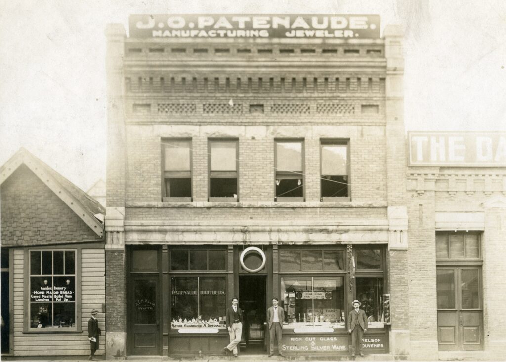 two story tall building with three men standing in front of front door. 'Patenaude' is written across the top.