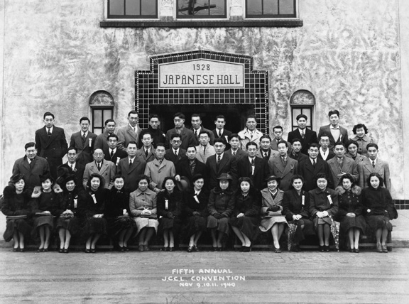 Image Courtesy of Nikkei National Museum. Around 40 Japanese Canadians pose for a photo in front of the Japanese Canadian Hall near Powell Street, Vancouver. Accession number 1992-32-3.