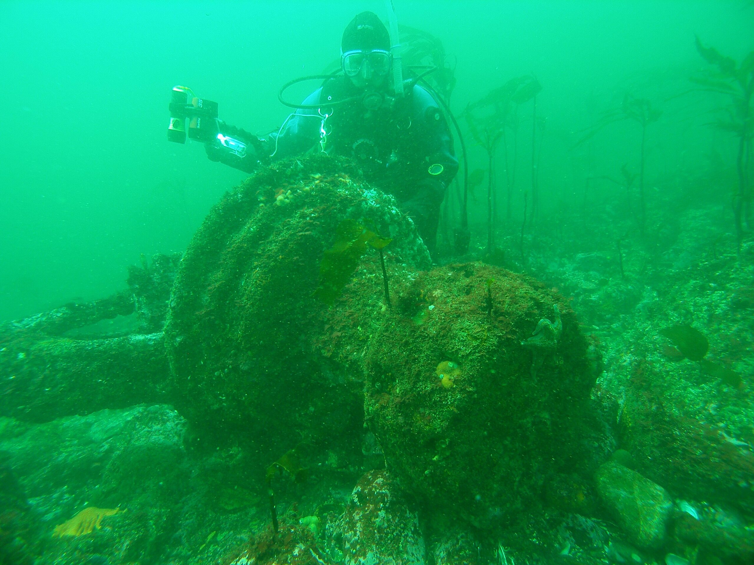 Diver posing on top of the rusted Melfort Capstan at the bottom of the ocean