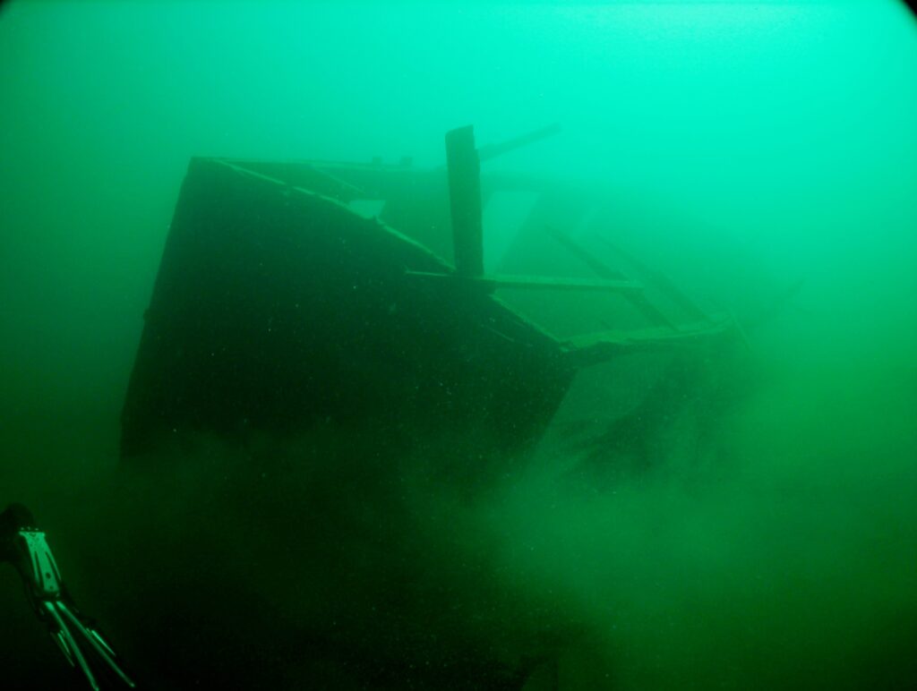 An image of a railcar in the murky green of Slocan Lake.