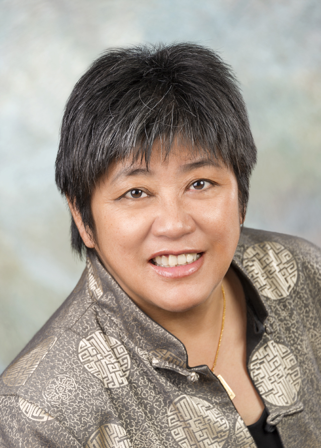 head shot of middle aged Chinese Canadian woman with short back hair and grey patterned jacket smiling
