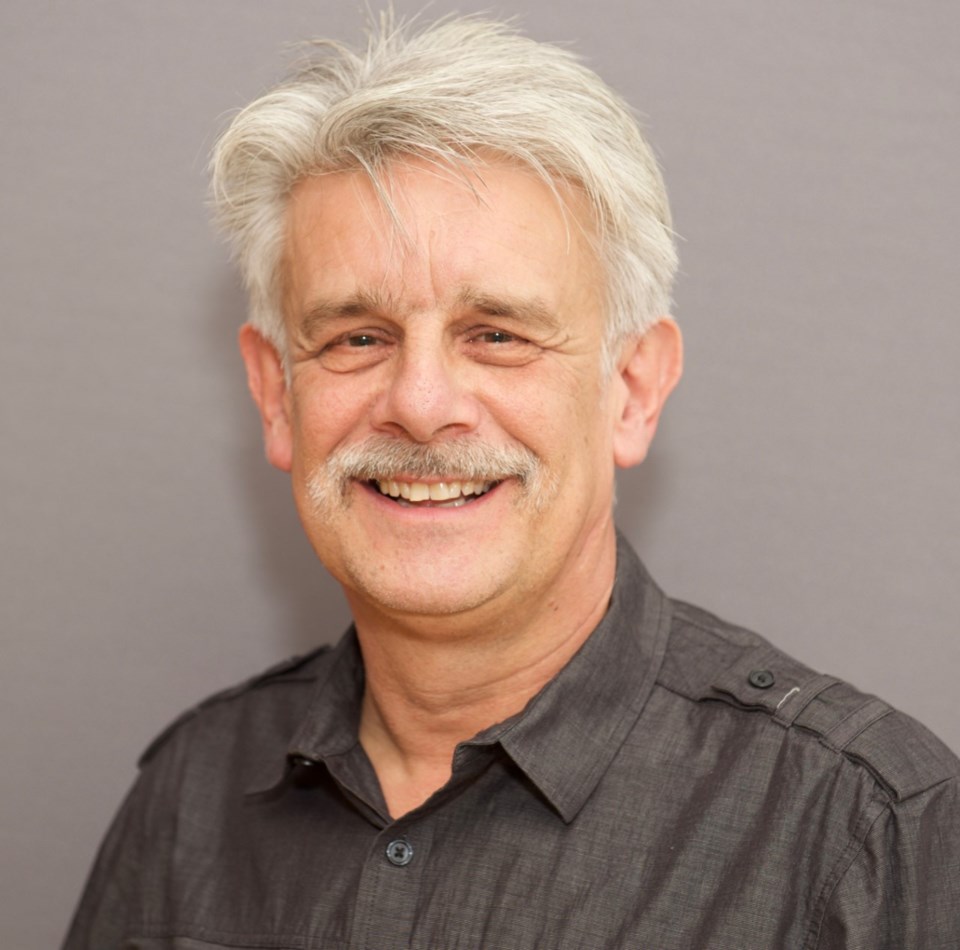 headshot of older white man with white hair and a white mustache wearing a grey button up shirt.