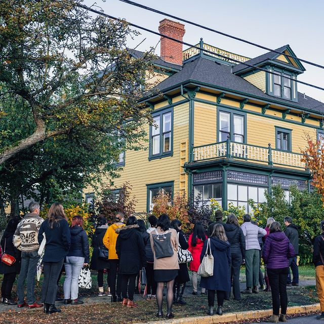 Walking Tour - group of around 20 stands looking at a historic house in Victoria's James Bay Neighbourhood