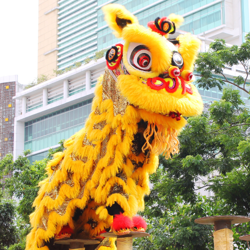 Chinese Lion dancer, a yellow lion with red accents, stands on a podium mid-dance