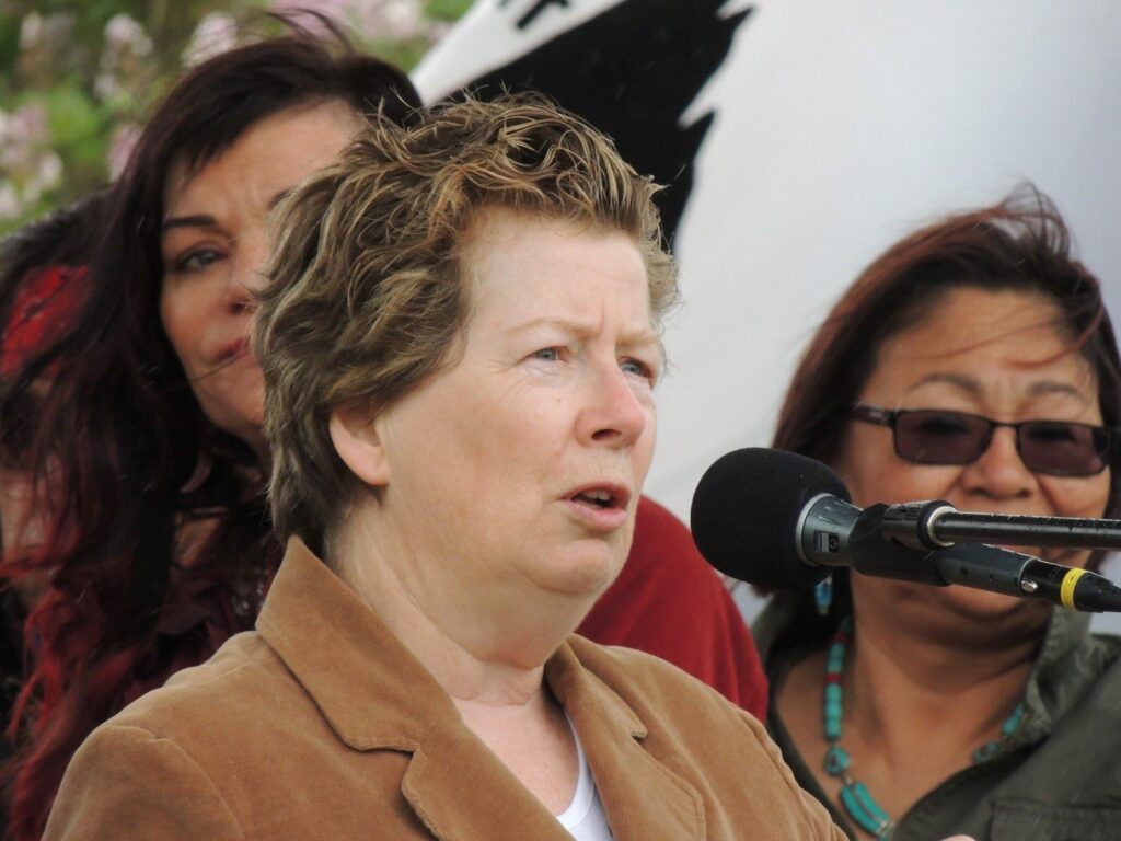 woman with short brown hair speaks into a microphone