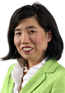 Japanese-Canadian woman with short black hair and green blazer and white collared shirt smiling