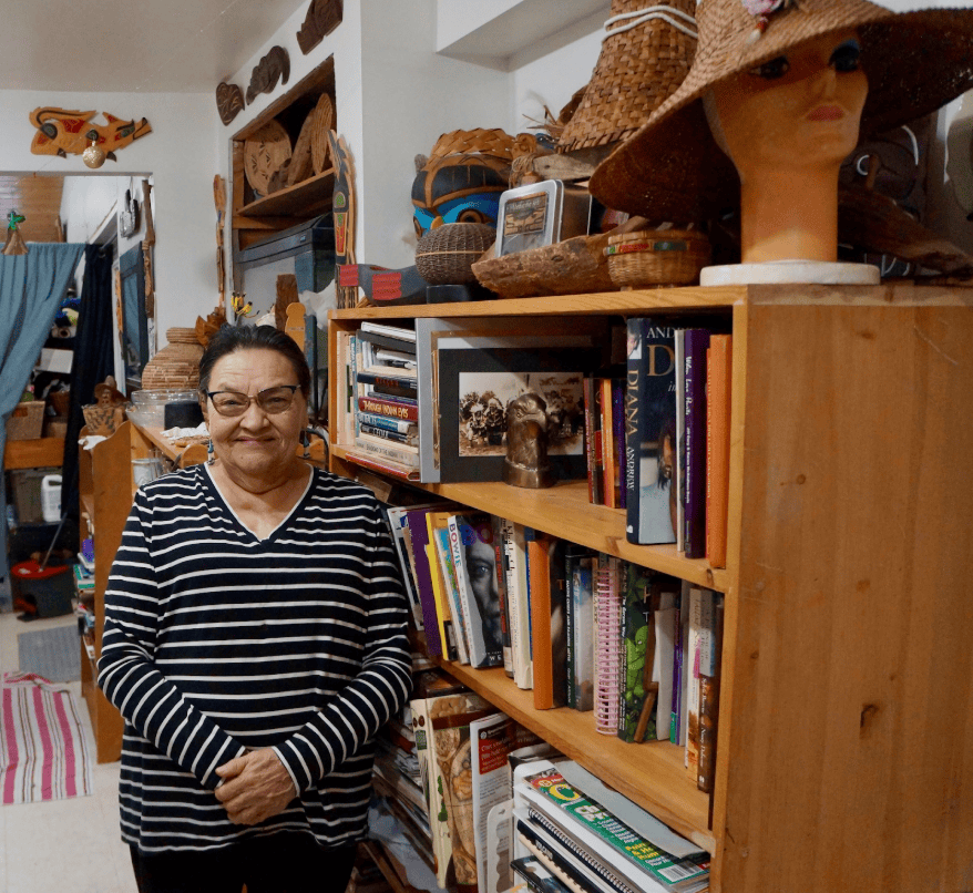 Woman smiling beside a bookshelf
